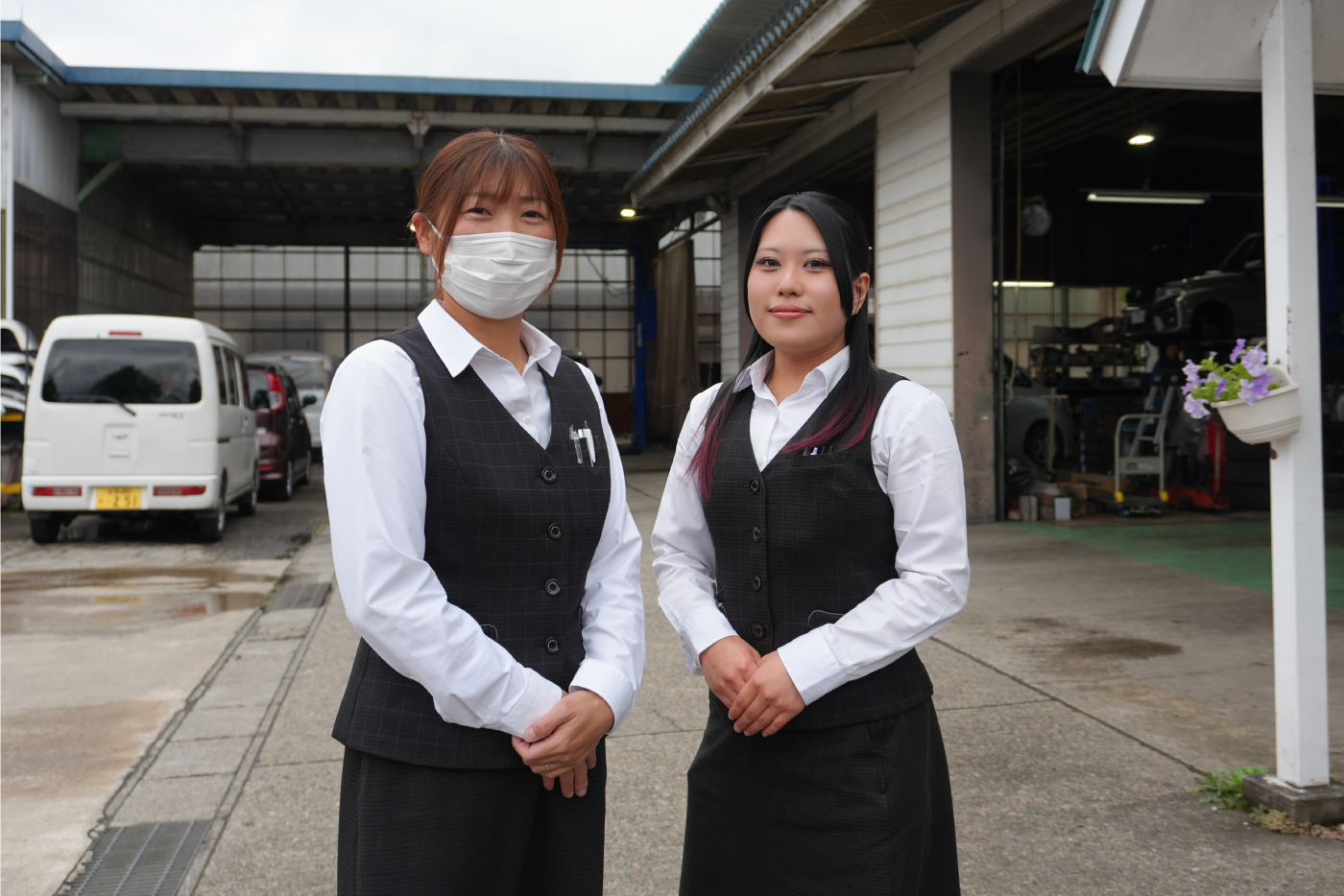 自動車工業で働く女性スタッフ2名が制服を着て立っている写真。